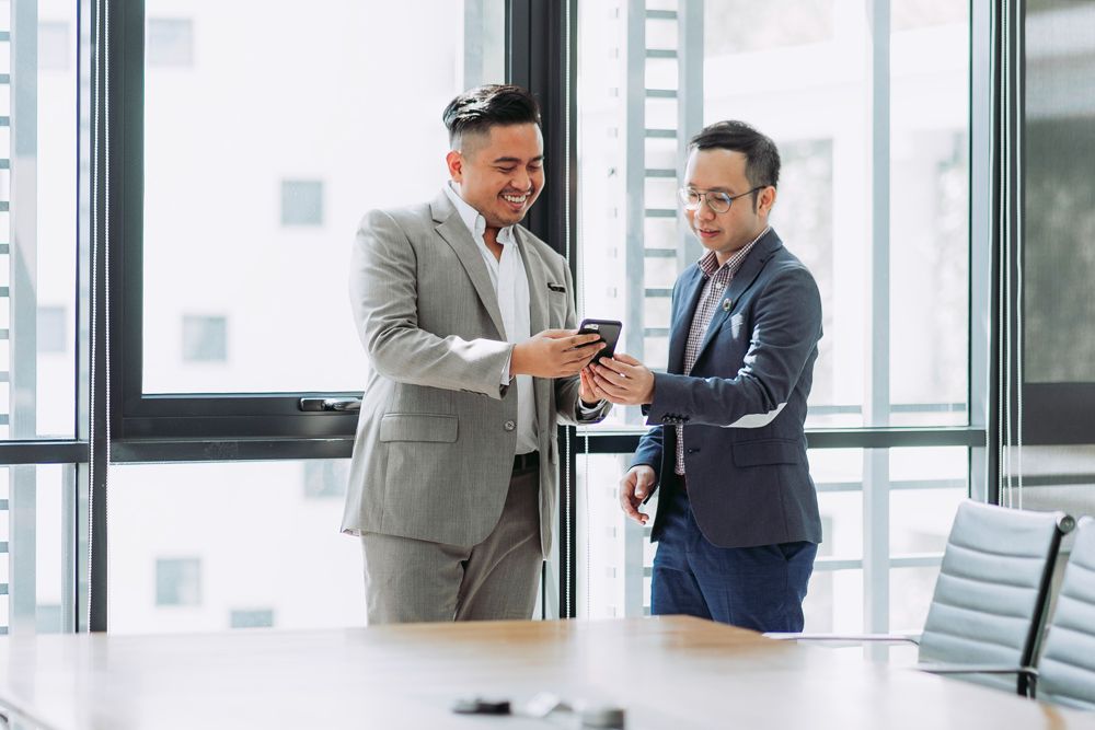 Property management professional smiling and using a mobile in modern office environment for property management software Australia