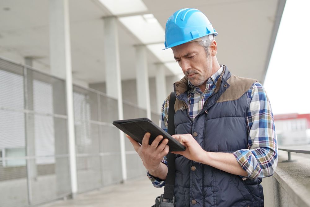 Construction architect using tablet at building site with MYBOS building management software