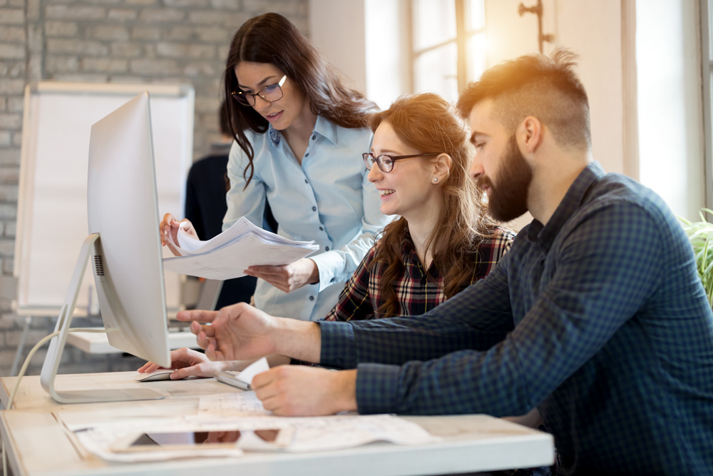 Three professionals collaborating over documents in modern office setting for property management software