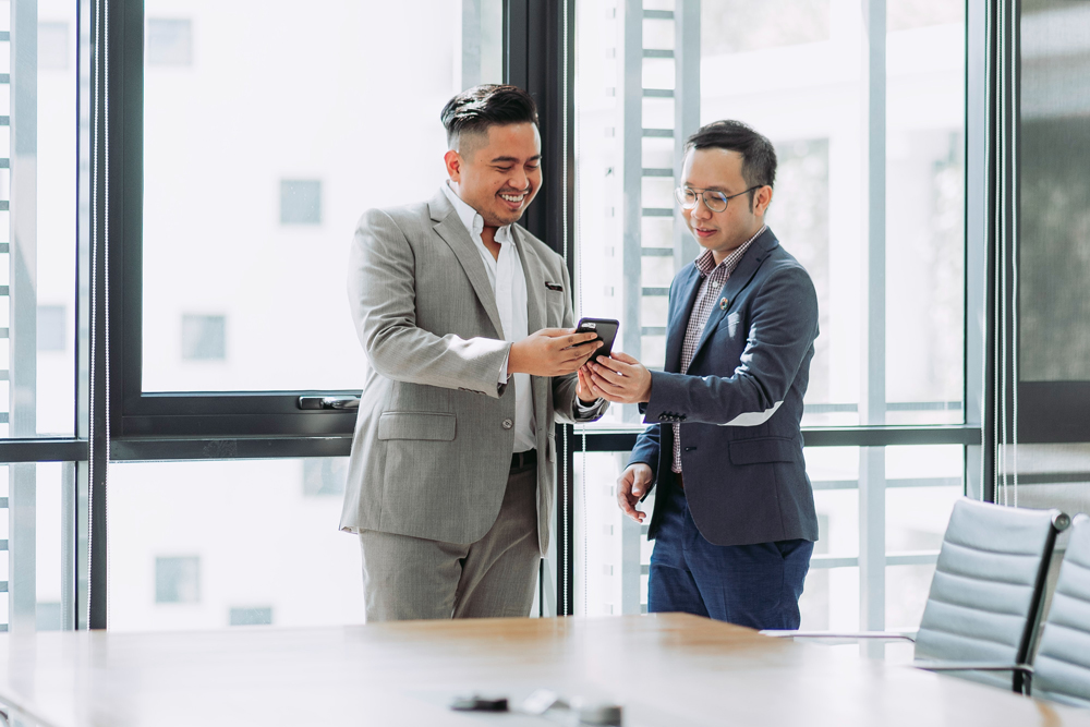 Property management professional smiling and using a mobile in modern office environment for property management software Australia