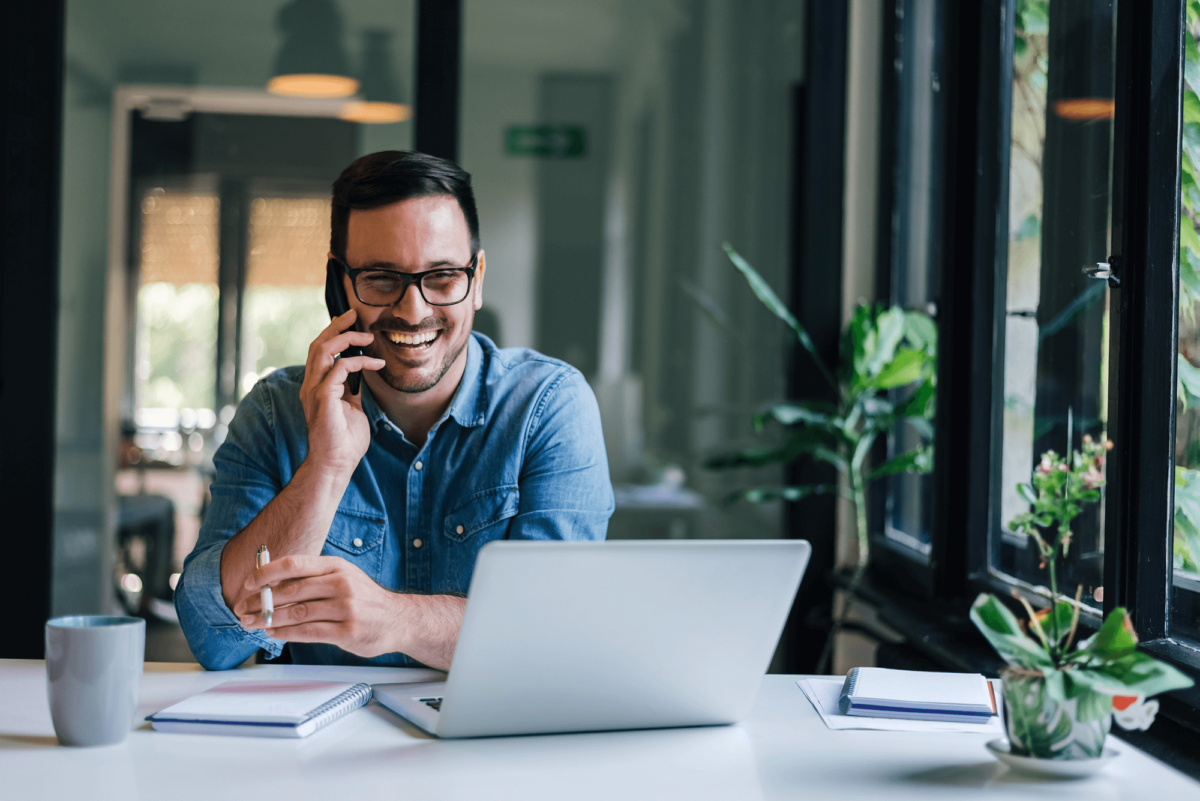 software Smiling professional using laptop and phone for property management software communication and collaboration