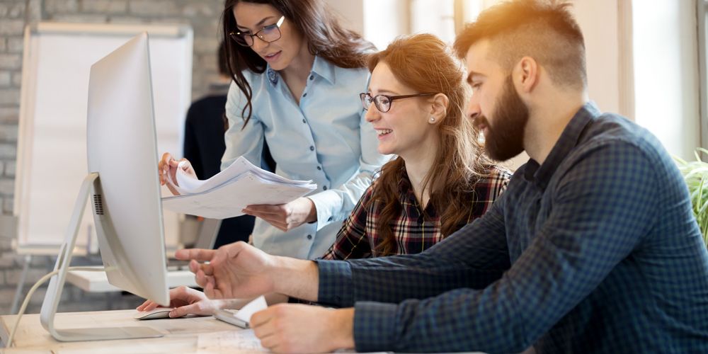 Three professionals collaborating over documents in modern office setting for property management software
