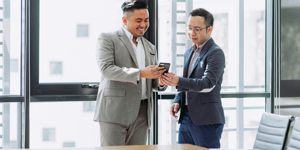 Property management professional smiling and using a mobile in modern office environment for property management software Australia
