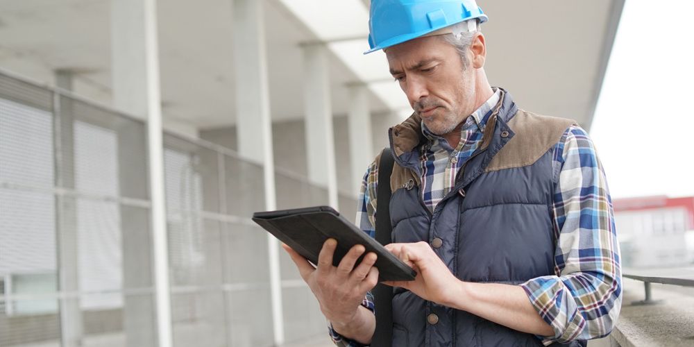Construction architect using tablet at building site with MYBOS building management software